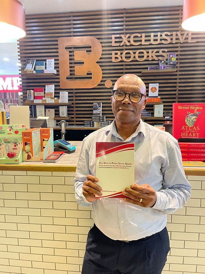 Temba Gola holds up a copy of his book in a bookstore